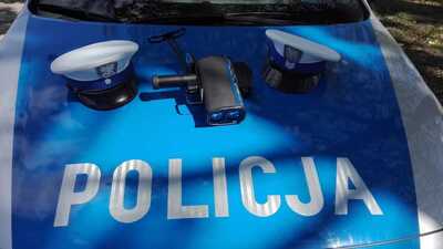 Czapka i ręczny miernik prędkości na masce radiowozu