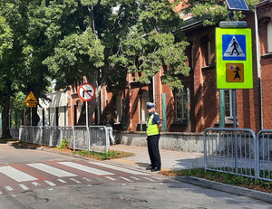 Policjant przy przejściu dla pieszych obok szkoły